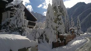 A snow-covered mountain landscape with a wooden cabin and a building with a sloped roof.