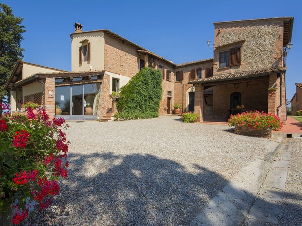 A traditional stone building with a gravel driveway and potted plants.