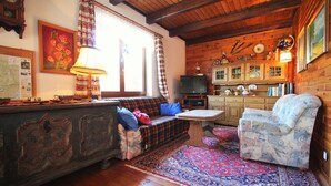 A cozy living room with a sofa, a patterned rug, a wooden cabinet, and a television.