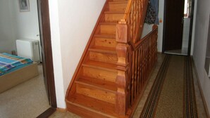 A wooden staircase leading to a second floor, a radiator, and a bed with a blue blanket.
