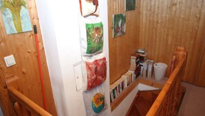 A wooden interior with a staircase, bookshelves, and artwork on the walls.