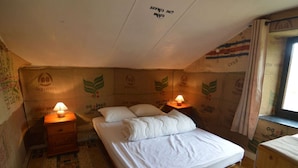 A small, cozy bedroom with a single bed, two bedside tables with lamps, and a window with curtains.