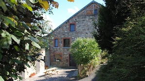 A stone building with a sloped roof, a wooden fence, and a picnic table in front.