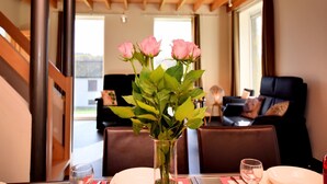 A dining table with a vase of pink roses, a glass of water, and a plate. - Cosy Holiday Home in Durbuy with Garden (Durbuy)