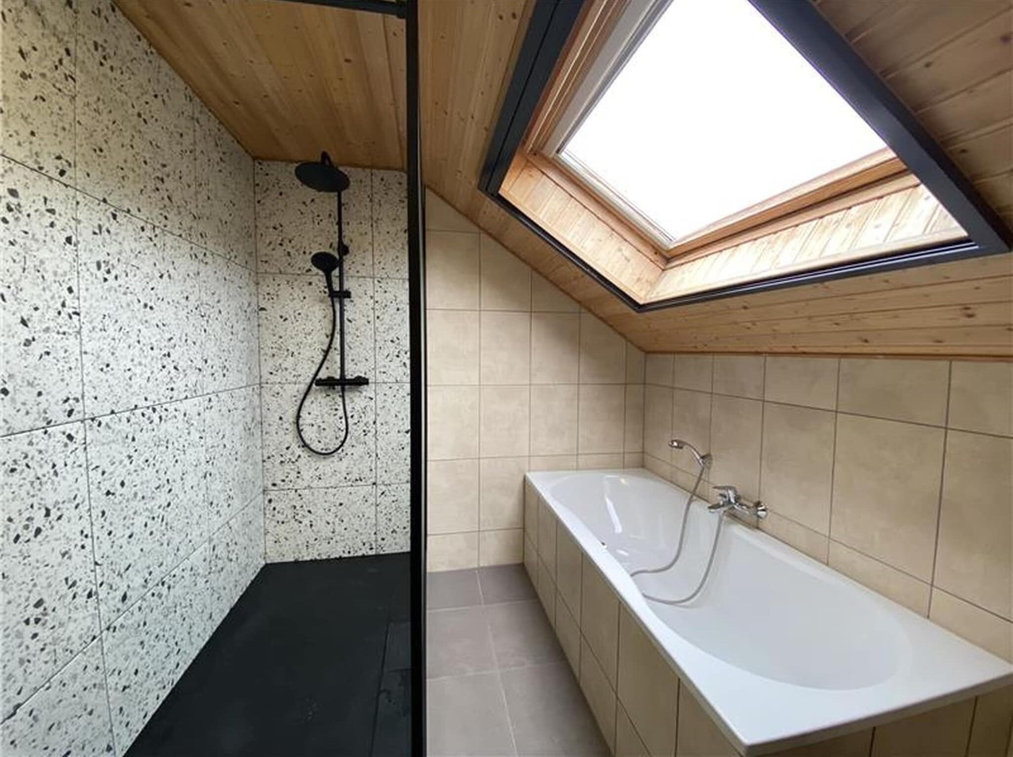 Une salle de bain moderne dotée d’une lucarne, d’une douche et d’une baignoire.