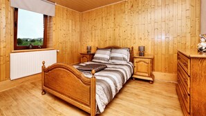 A wooden-paneled bedroom with a bed, bedside tables, and a dresser. - Holiday Apartment with Garden in Born (Born (Amel))