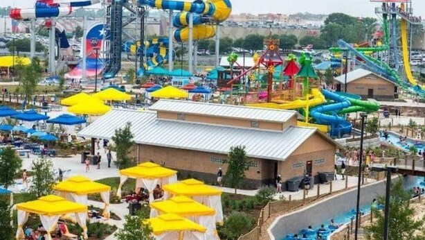Een waterpark met diverse glijbanen en zwembaden, tenten en een overdekt zitgedeelte.