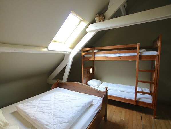 Una habitación tipo dormitorio con literas, un tragaluz y suelo de madera.