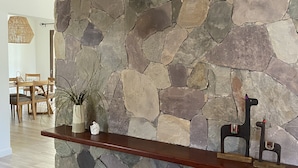 Un mur en pierre sur lequel est fixée une étagère en bois, servant à exposer des objets décoratifs.