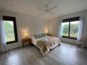 A bedroom with a bed, nightstands, a chair, a ceiling fan, and large windows with curtains. - ACODEGORA Y AMPLIA CASA EN SALTA (Villa San Lorenzo)