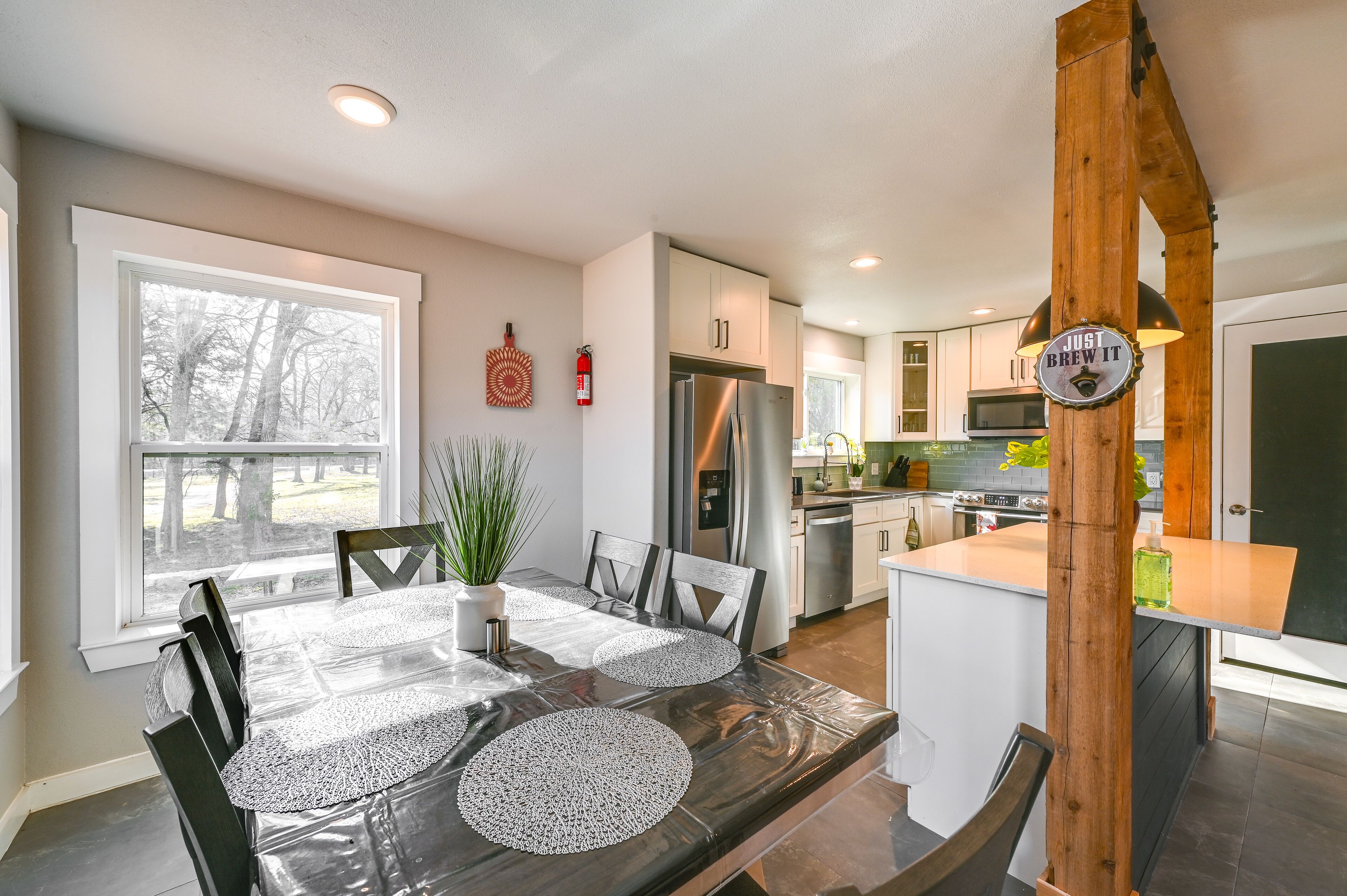 A modern kitchen with a stainless steel refrigerator, a wooden island, and a dining area with a glass table and chairs.