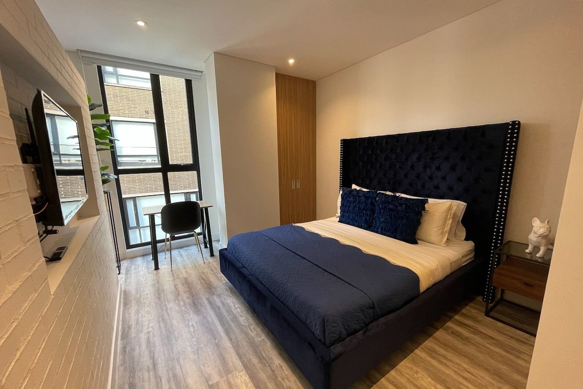 A modern bedroom with a large bed, a desk, and a chair.