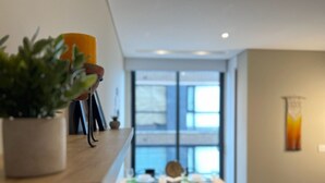 A modern interior with a dining area, a potted plant, and a window with a view.