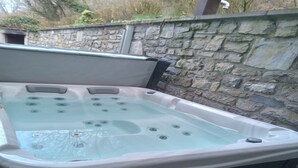 A hot tub with multiple jets, set against a stone wall. - Cottage with Bubble Bath (Clavier (les Avins))