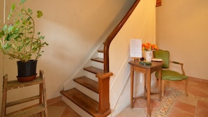 A staircase with wooden steps and a handrail, a potted plant, a small table with a vase of flowers, and a chair. - Holiday Home with Garden, Heating, Barbecue (Butgenbach)