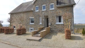 A stone house with a gabled roof, a front door, and a small porch. - Holiday Home in Ardennes with Scenic Garden (Halenfeld-Amel)