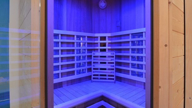 Un sauna doté de plusieurs bancs en bois et d’une horloge au mur.