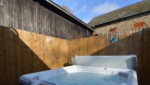 Un bain à remous dans un espace extérieur en bois, agrémenté d’un mur en pierre et de découpes d’animaux.
