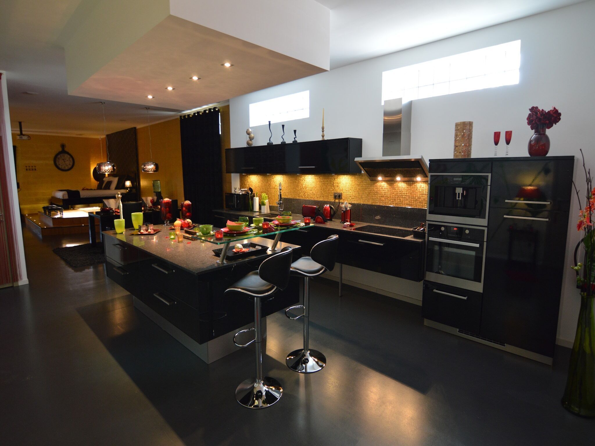 A modern kitchen with a central island, bar stools, a built-in oven, and a refrigerator.