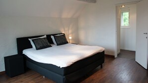 A bedroom with a black bed, white bedding, and a wooden floor.