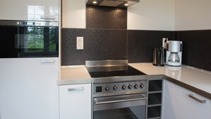 A modern kitchen with a built-in oven, stovetop, and coffee maker.