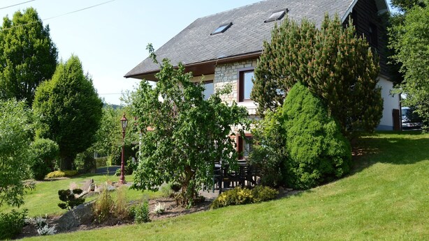 A house with a stone facade, a sloped roof, and a garden with various trees and shrubs. - Ondenval Stay with Sauna (Waimes-Ondenval)