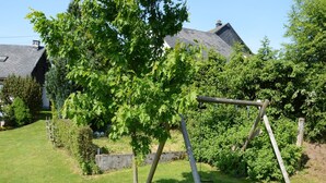 A wooden swing set in a grassy yard with a house in the background. - Ondenval Stay with Sauna (Waimes-Ondenval)