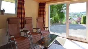 A room with three reclining chairs, a small table, and a view of a parking area and greenery outside. - Ondenval Stay with Sauna (Waimes-Ondenval)