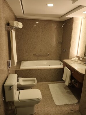 Een badkamer met een bad, toilet, bidet en wastafel.