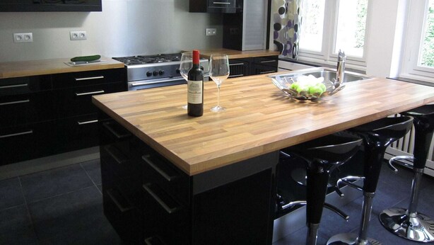 Een moderne keuken met een houten kookeiland, roestvrijstalen apparatuur en een schaal met fruit.
