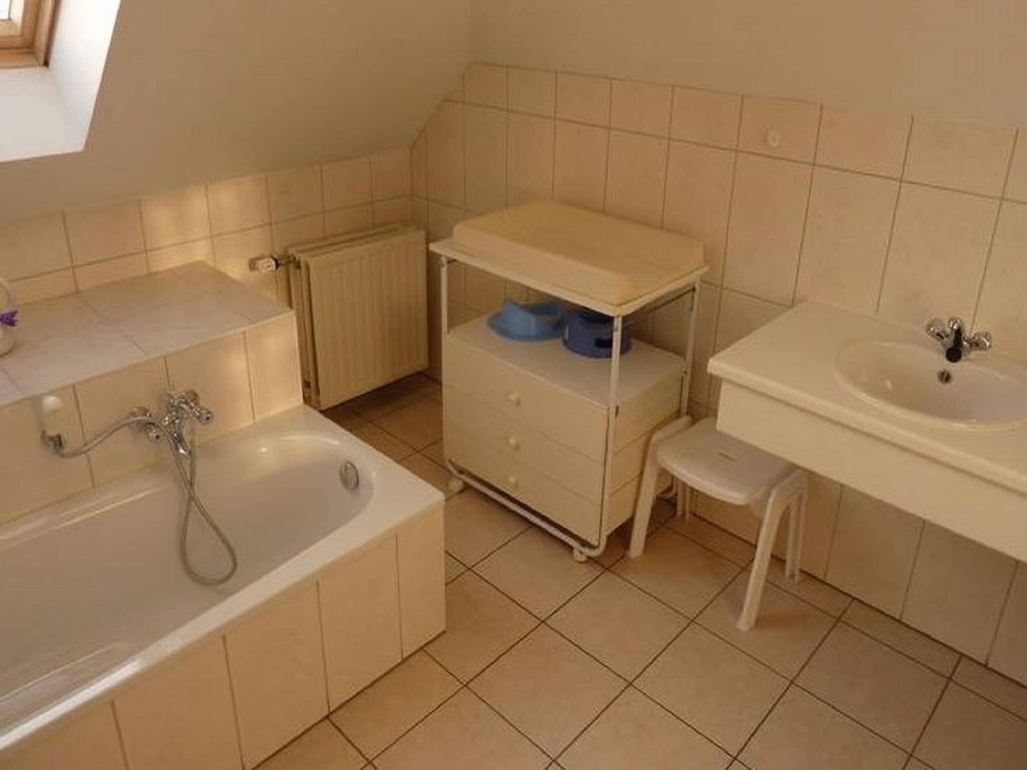 Een badkamer met een bad, een wastafel en een klein krukje.