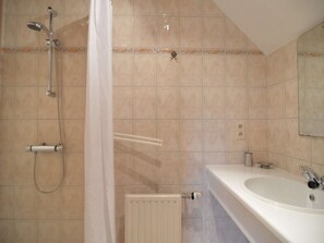 Un baño con ducha, inodoro, lavamanos y radiador.