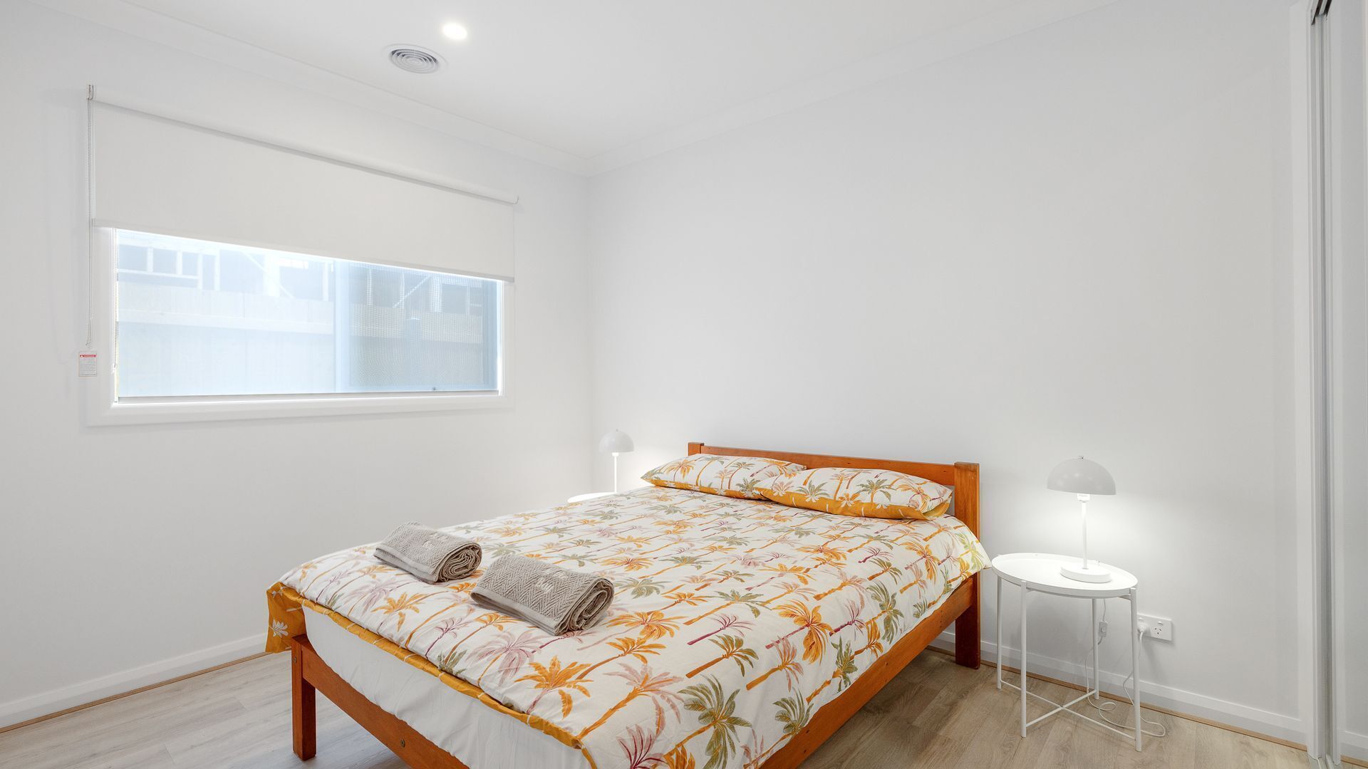 A bedroom with a bed, a window, a bedside table, and a lamp.