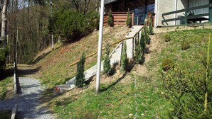A modern house with a wooden deck, a staircase leading to a covered porch, and a gravel path.