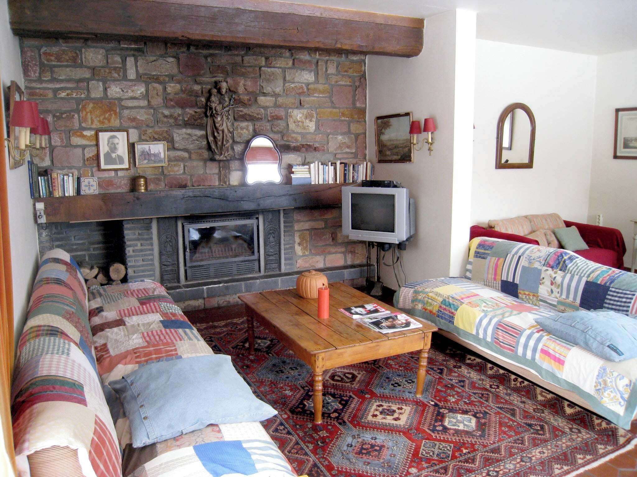 A cozy living room with a fireplace, a television, and a patterned rug.