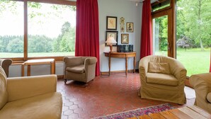 A room with a large window, two armchairs, a small table, and a rug. - Rustic Retreat in Houvegné (Stavelot)