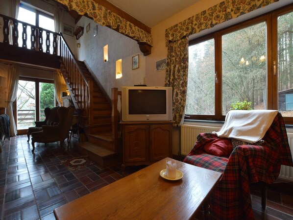 Un salon chaleureux avec un escalier en bois, un téléviseur et un canapé à carreaux.