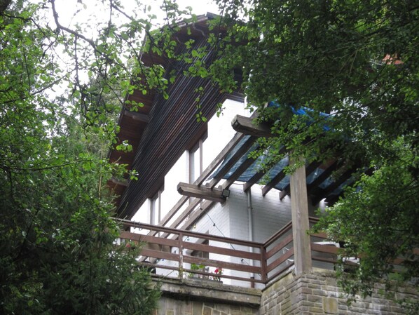 Eine traditionelle Holzhütte mit einem Balkon, umgeben von dichtem Grün.