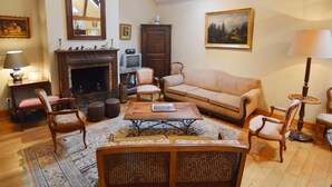 A traditional living room with a fireplace, a sofa, a coffee table, and a dining table. - Cosy Cottage in Barvaux-Condroz with Garden (Barvaux Condroz)