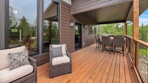 A wooden deck with wicker furniture and large windows. - Stylish home with hot tub, pool access, wifi and garage (Lead)