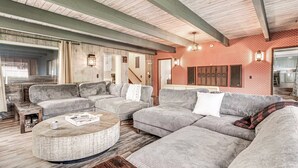 Una sala de estar amplia con un sofá seccional grande, una mesa de centro redonda y una chimenea.