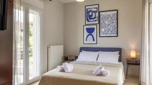 Ein Hotelzimmer mit einem Bett, zwei Nachttischen, einem Fenster mit Vorhängen und einem Kunstwerk an der Wand.