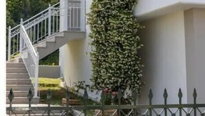 Ein mehrstöckiges Gebäude mit weißer Fassade, einer Treppe mit weißen Geländern und einer vertikalen Begrünung an einer Seite.
