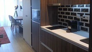 Une cuisine moderne avec des meubles en bois, un four à micro-ondes, une machine à café et un dosseret carrelé.