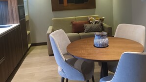Un salon moderne comprenant une table à manger, deux chaises, un canapé et un élément décoratif mural.