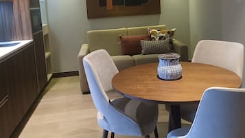 Una sala de estar moderna con una mesa de comedor, dos sillas, un sofá y un adorno de pared.