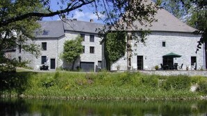 A stone building with a pond in front, featuring a patio with outdoor furniture.