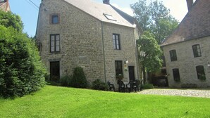 A stone building with a sloped roof, a small porch with chairs, and a cobblestone courtyard. - Alpine Getaway in Neustift (Treignes)