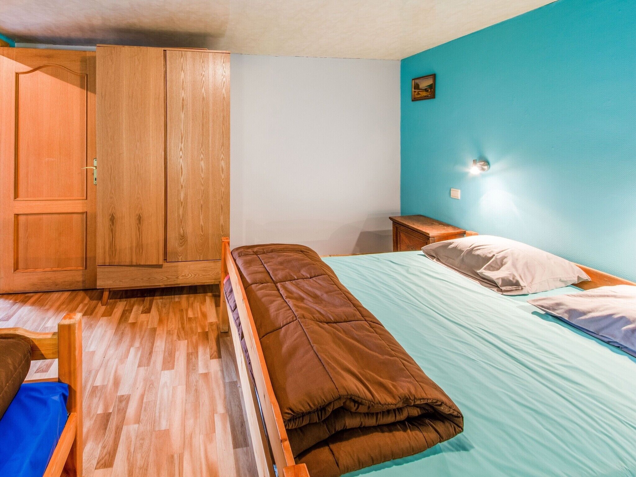 Een slaapkamer met een bed, een kledingkast en een nachtkastje.