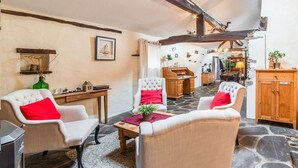 A cozy living room with stone flooring, a fireplace, and a dining area with wooden furniture.